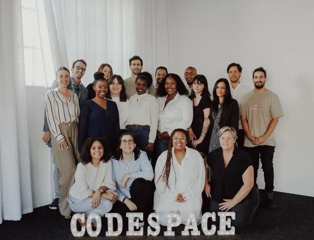 The CodeSpace team gathered behind the CODESPACE letter lights